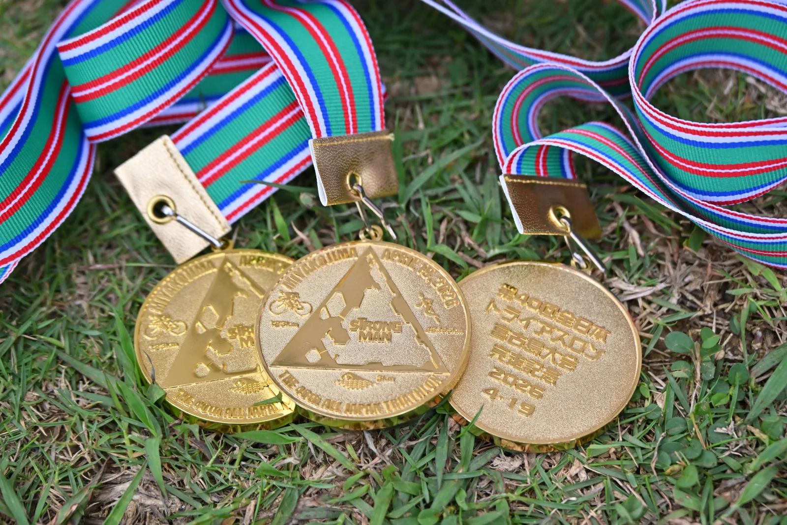 The Miyakojima finisher medal, gold with swim, bike, and run relief