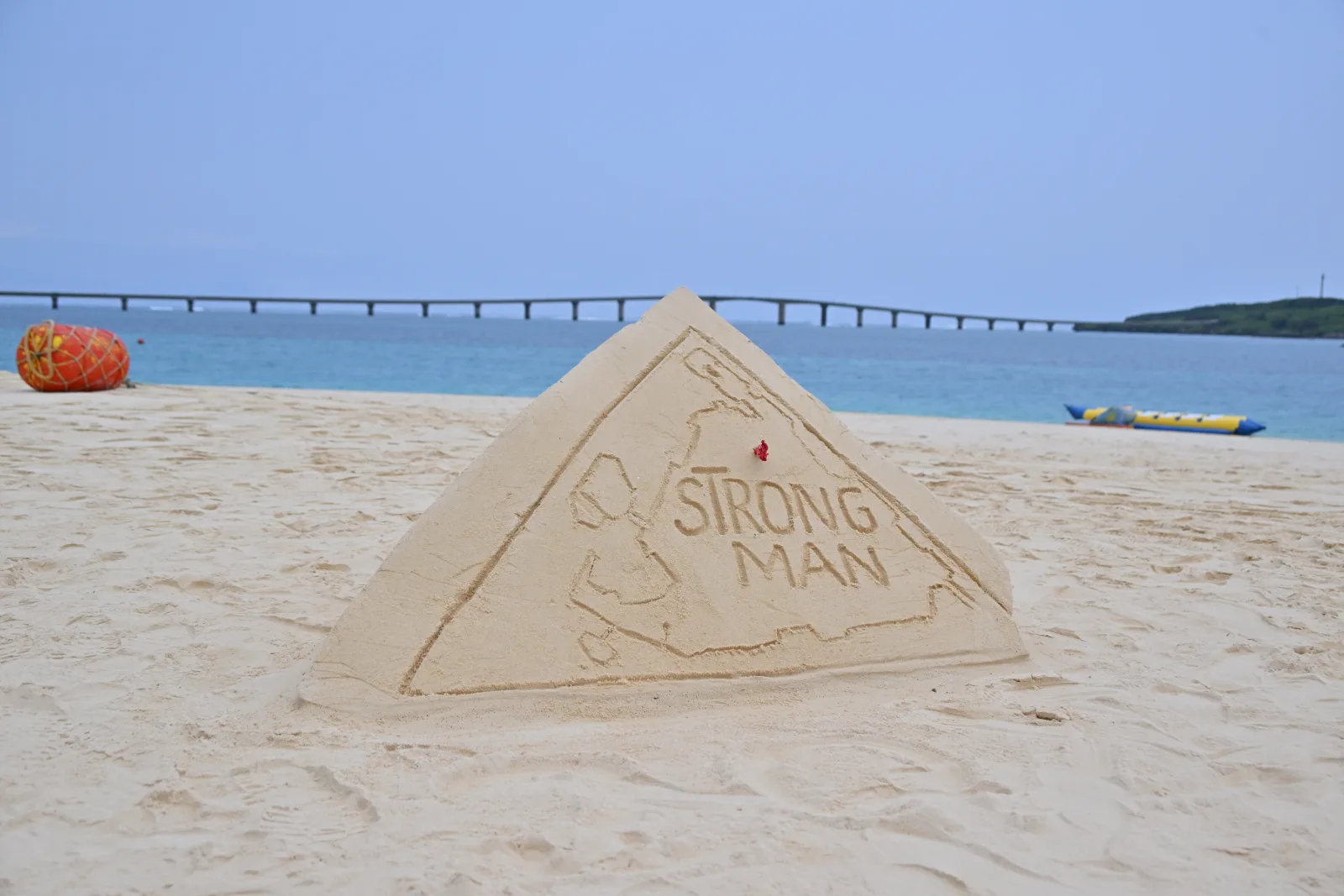 Yonaha Maehama the day before the race. A sand sculpture of the island with “STRONG MAN” carved in, and the Kurima Bridge in the distance